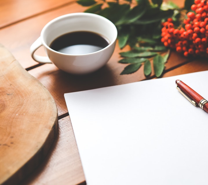 Blank paper with pen and coffee on a table.